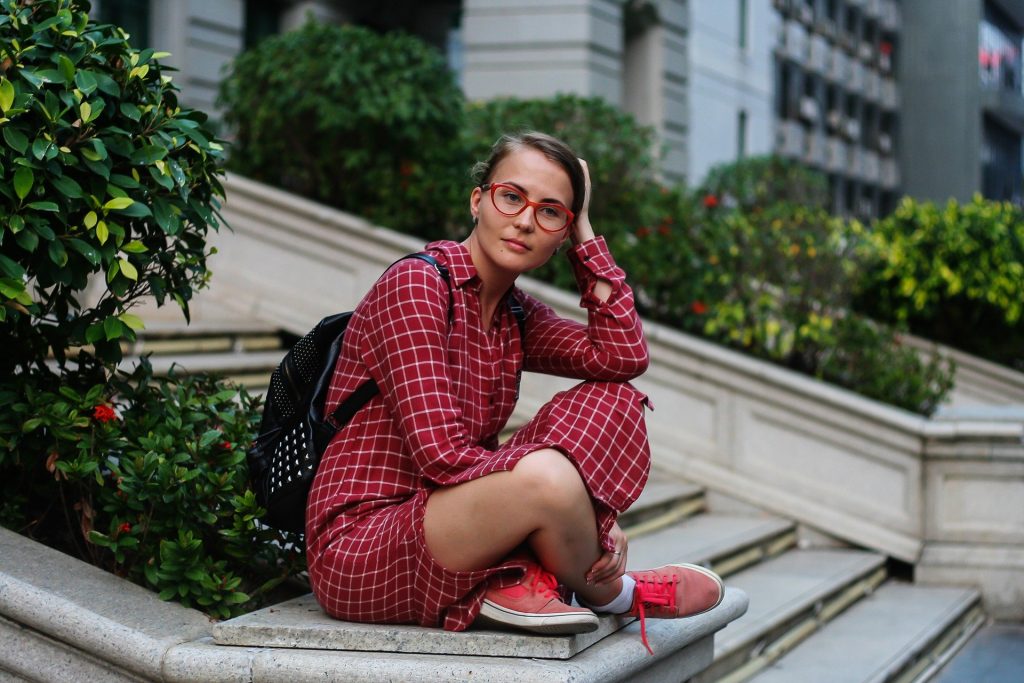 Una chica con gafas rojas sentada en una escalera