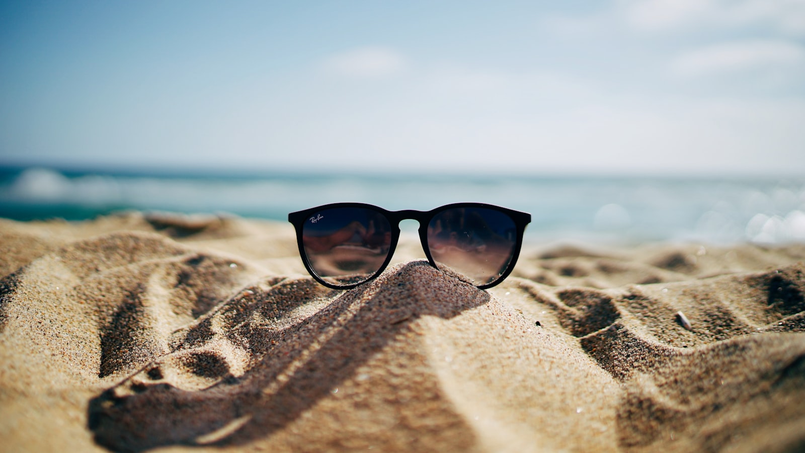 Gafas de sol apoyadas sobre la arena de la playa